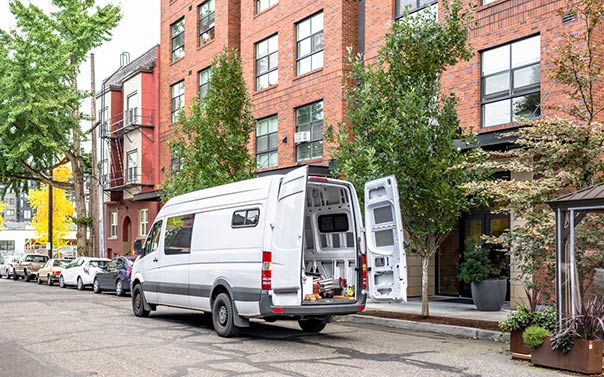 a white commercial van with back door open exposing tools in a metro area
